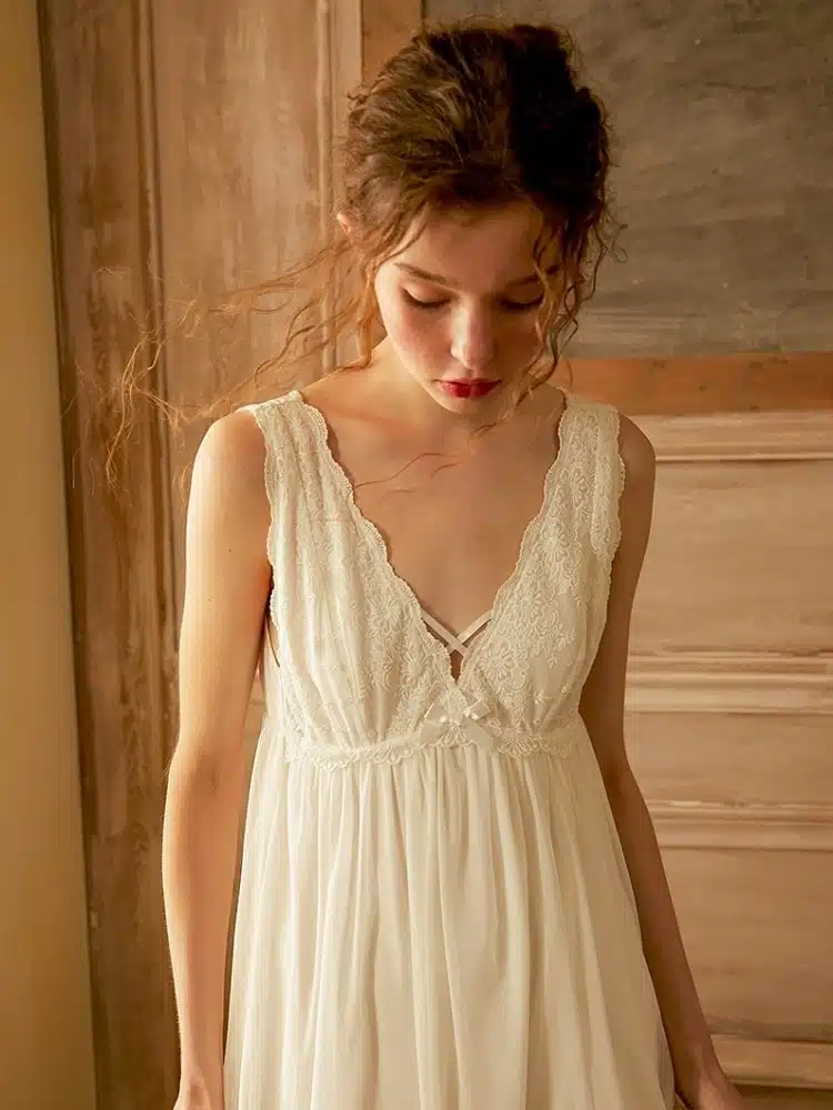 Femme qui porte une robe de nuit vintage blanche sans manches pour femme et qui regarde vers le bas