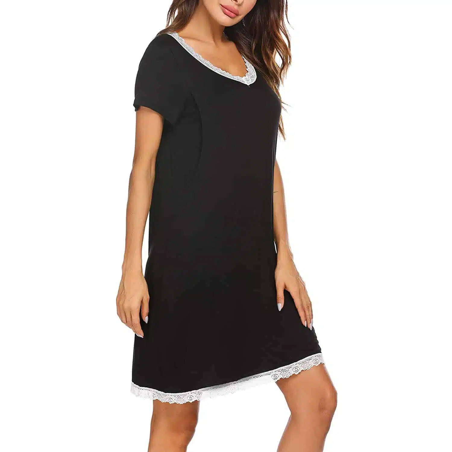 Une femme debout qui porte une robe de nuit de maternité noire. Une dentelle blanche orne l'encolure et le bas de la robe. Sur fond blanc.